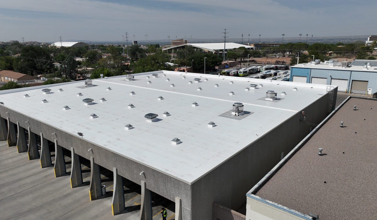 A large building with many parking spaces and a white roof.